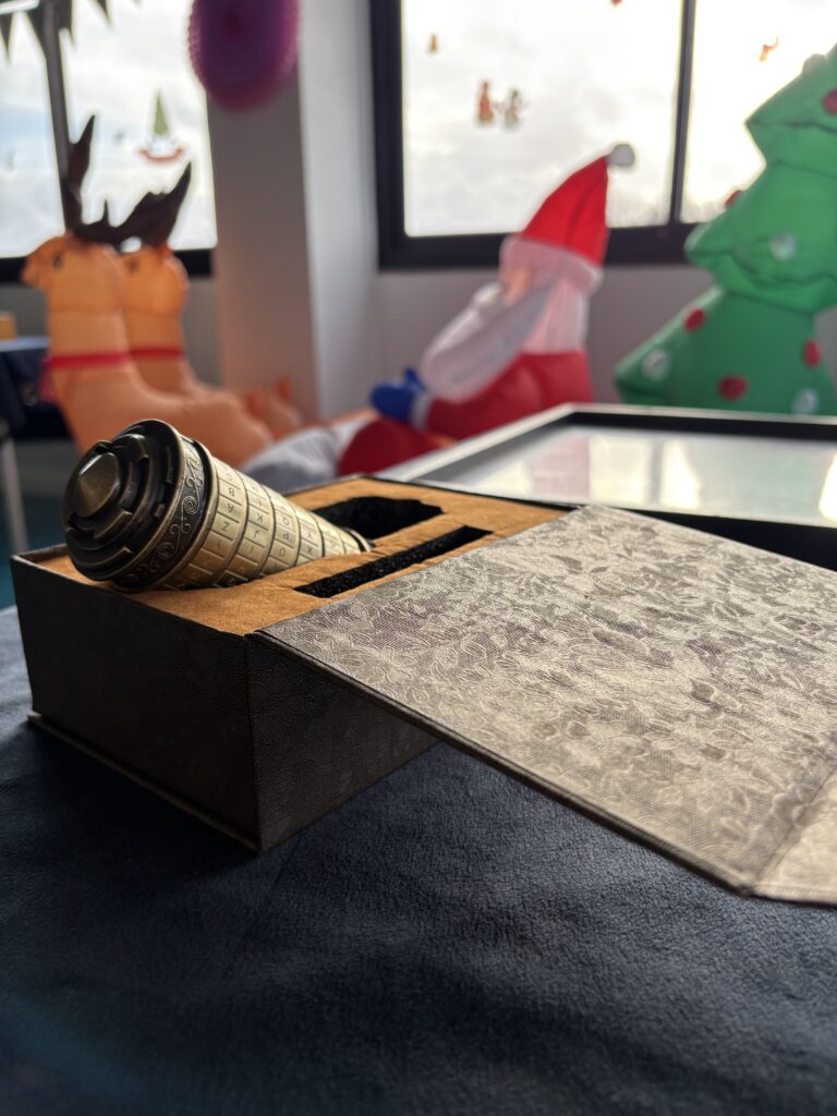 Cryptex dans son coffret devant des décors de Noël gonflables, énigme de La Magie de Noël
